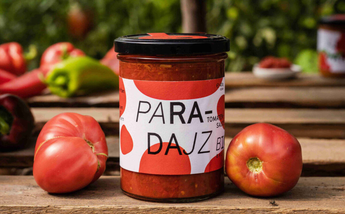 Ein Glas Bio-Paradajz mit Tomaten am Brett