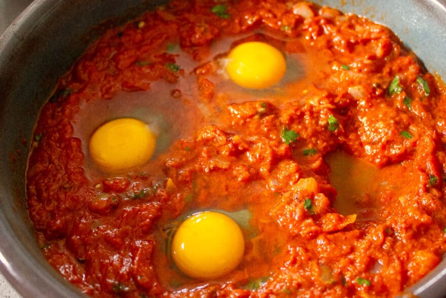 Rohe Eier in der Shakshuka-Masse vor dem Garen